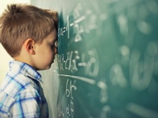 Frustrated boy with head on chalkboard